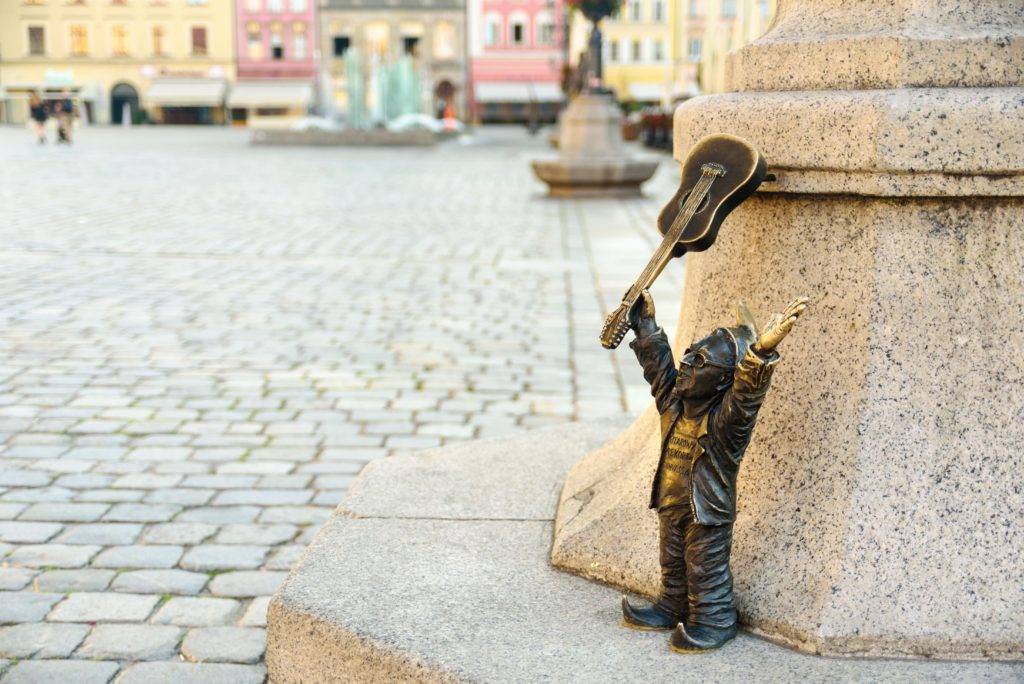A metal dwarf statue holding an acoustic guitar in the city of Wroclaw, Poland