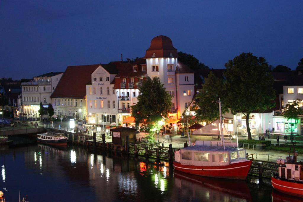 A photo of Hotel Am Strom from across the canal in Warndemunde at night.