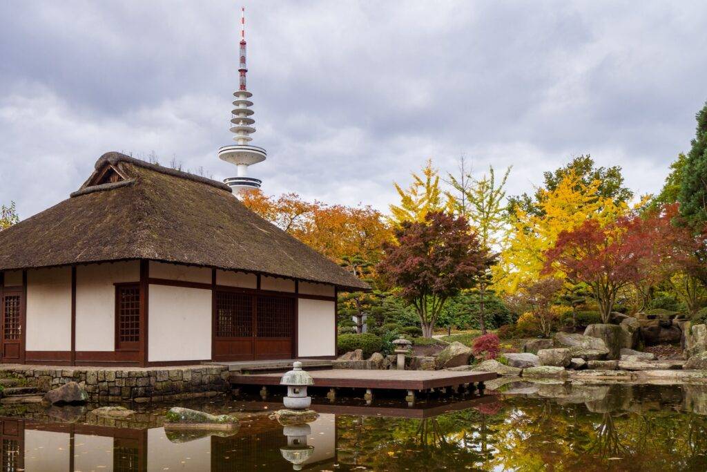 A Japanese style building surrounded by water and autumn trees
