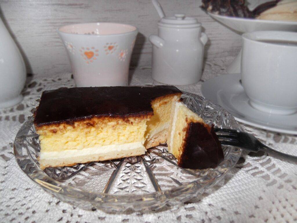 A slice of layered Eierschecke cake on a glass place